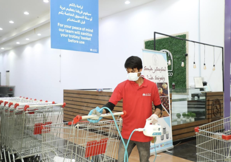 A worker cleans shopping carts in Saudi Arabia for customers.